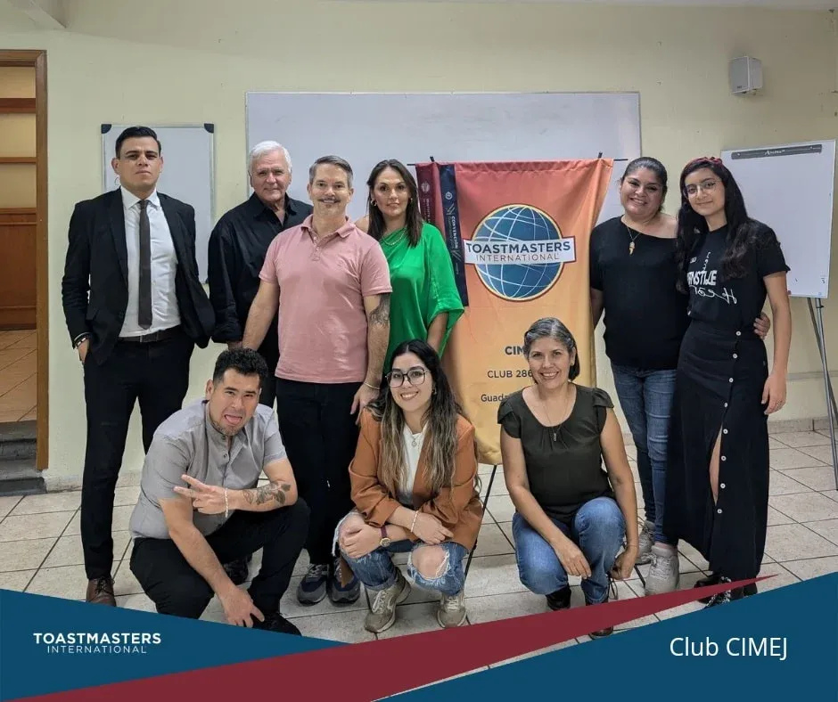 Miembros del club CIMEJ reunidos junto a la bandera de Toastmasters